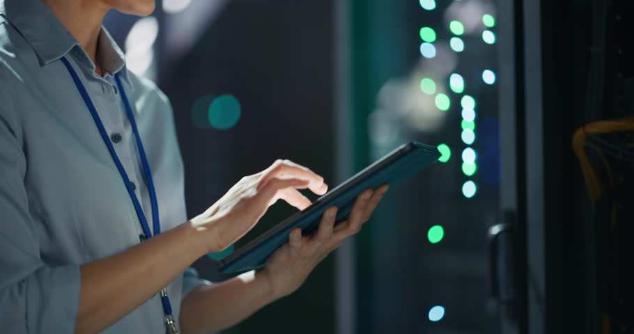 Close Up Footage of an Anonymous IT Specialist Using Tablet Computer in Data Center. Server Farm Cloud Computing Facility with a System Administrator Working with Cybersecurity and Network Operations