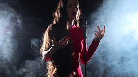 Singer in a dress with a microphone in her hands sings in the rays of spotlights and a smoky stage - Powered by Shutterstock - Get 15% off with code: PIKWIZARD15