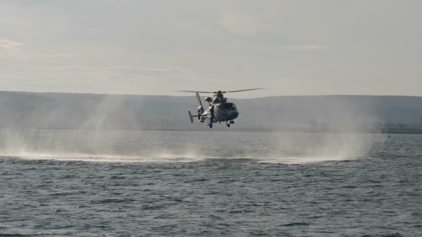 Coast Guard rescuers jump from a helicopter hovering over the sea, on-board rescuers, training for rescue in extreme conditions