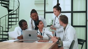 Multiethnic medical team analyzing patient data on laptop and x-ray results, collaborating on diagnosis and treatment plan in hospital meeting room - Powered by Shutterstock - Get 15% off with code: PIKWIZARD15