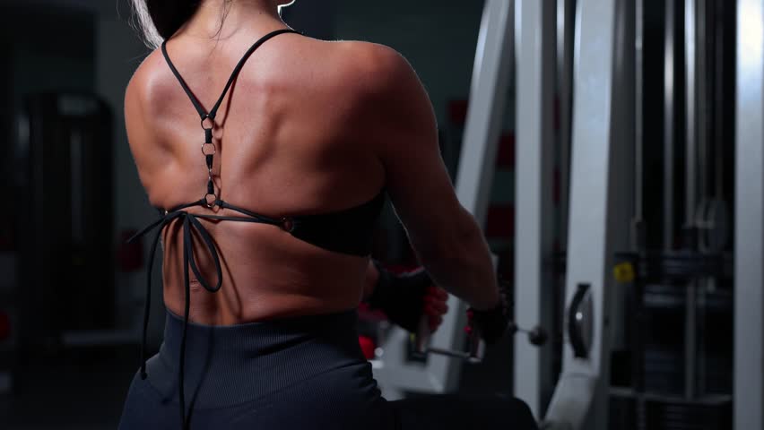 Muscular woman working out in gym doing exercises for back. Strong fitness girl, muscles back