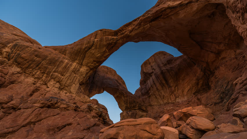 Time-lapse capturing golden sunrise over Double Arch, Arches National Park, Utah. Morning light on sandstone