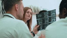 Professional medical team, including diverse doctors, examining and discussing brain scan images during a consultation in a hospital setting - Powered by Shutterstock - Get 15% off with code: PIKWIZARD15