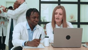 Multiethnic medical team discussing patient case, male and female doctors reviewing laptop data, colleagues analyzing x-rays in medical facility background - Powered by Shutterstock - Get 15% off with code: PIKWIZARD15