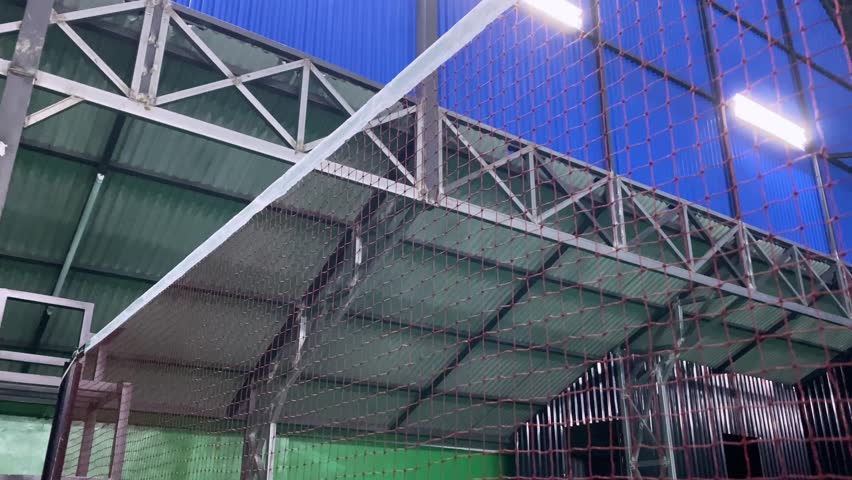 a white shuttlecock hitting the net in slow motion during a badminton game in an arena