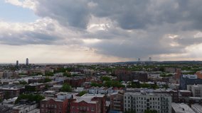 Aerial view of Bensonhurst, Brooklyn in the late afternoon just before a rainstorm. Sunlight breaks through dramatic clouds, casting warm highlights over residential rooftops and tree-lined streets. T - Powered by Shutterstock - Get 15% off with code: PIKWIZARD15