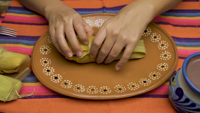 Person opening a tamale with his hands. Tamale, typical Mexican food.