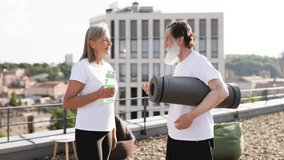 Outdoor portrait of senior man and woman, holding yoga mat and water bottle, rooftop city background. Depicts health, fitness, outdoor activities, active lifestyle for elderly individuals. - Powered by Shutterstock - Get 15% off with code: PIKWIZARD15
