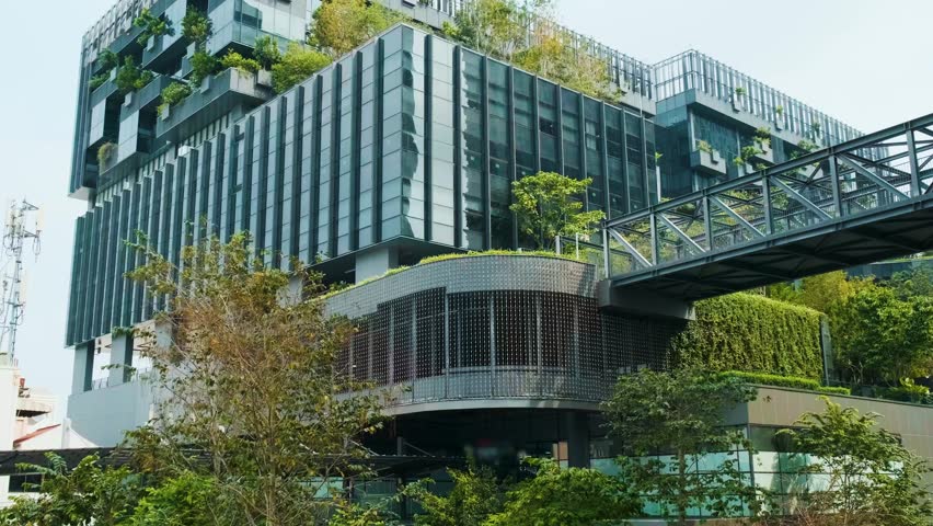Modern eco-friendly glass office building with vertical garden and skywalk bridge in urban environment in Bangkok city, Thailand. Green architecture and sustainable design for reduce carbon dioxide