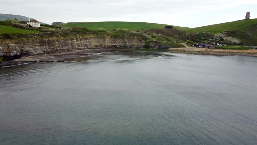 Drone footage moving around Limmeridge Bay, Dorset. Rotating around from inside the bay around the edge to show the lighthouse on top of the cliff.