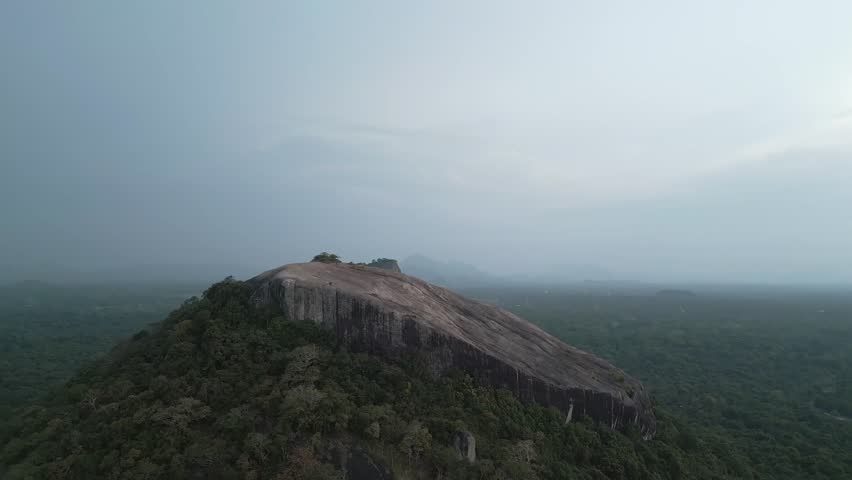 Aerial rising view visitors hiker on top viewpoint of Pidurangala Rock with Sigiriya rock view and the lush green jungle in Sri Lanka Cultural Triangle