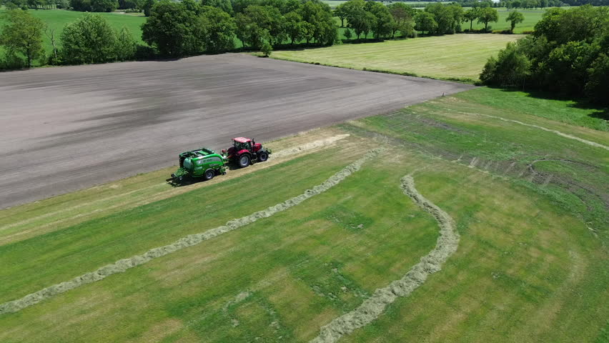 Aerial shots of tractor with bale wrapping machine. Making hay bales at a meadow in the Netherlands. Baling. Farming.
