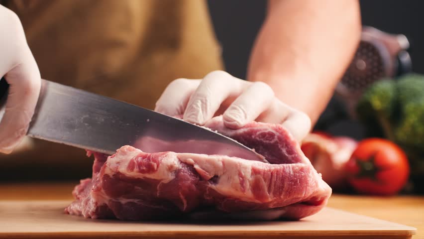 Man cut meat steak, beef pork neck cooking, Cook Butcher. The chef cuts the meat for cooking. Neck carbonate with vegetables cutting on ktchen for bbq grill, marinade. 