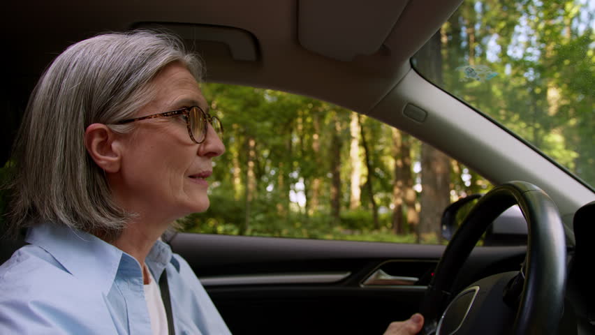 Road rage mad furious woman older mature female elderly lady car auto driver riding inside automobile riding vehicle traffic accident yelling shouting gesturing hands aggression rudeness complaining