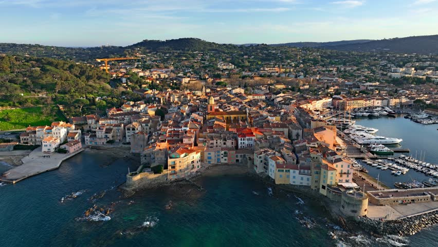 Aerial view of Saint-Tropez's colourful houses, church tower on the French Riviera. View from above of public beach and Catholic church, Cote d'Azur, a popular destination for travel in Europe