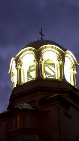 Vertical night shot of Alexander Nevsky Cathedral in Sofia, Bulgaria. Golden bells and domes shine under city lights. A majestic view of this historic Orthodox landmark.