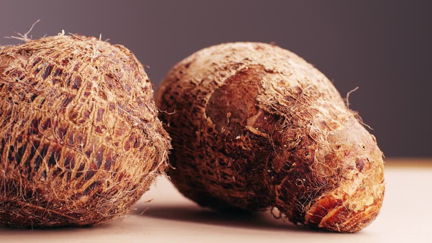 Taro vegetable tubers, Stack of raw, unpeeled tropical taro, Colocasia esculenta, on a market stall