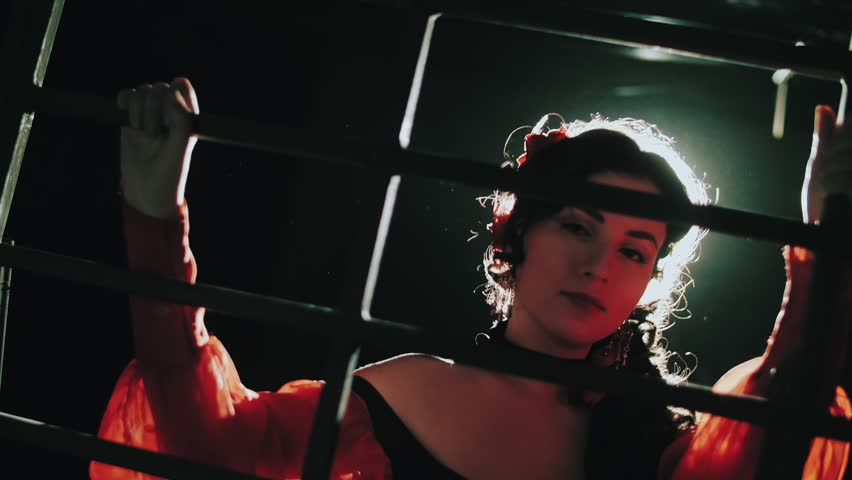The girl behind bars is trying to seduce the guard. Seduction. Women's prison. The concept of the Carmen opera.