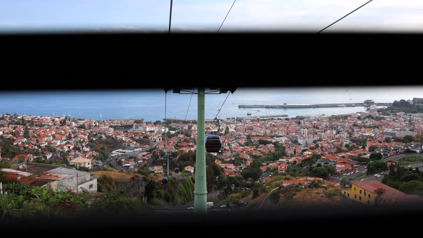 Aerial view of cable car, providing a perspective of the city of Funchal, landscape and coastline. Madeira Island, Portugal