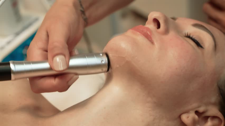 Lady experiencing refreshing facial treatment by seasoned beautician in day spa. Non-Invasive Anti-Aging Technology, Ultrasound Beauty Therapy. Facial therapy, skincare routine, anti-aging aesthetics