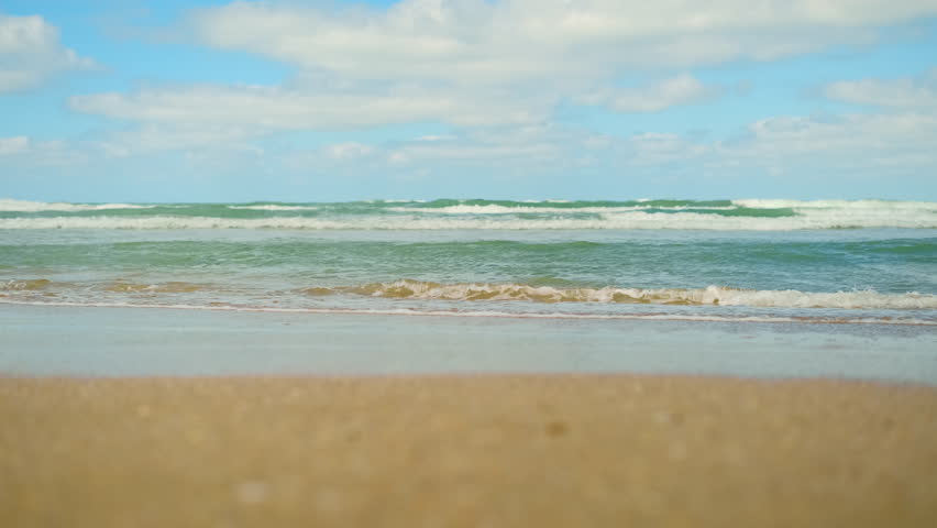 Sea waves roll on sandy shore in rhythmic motion, beach footage after a storm, waves attract attention with wild coastal energy and invite you to swim in sea, concept for advertising a beach holiday
