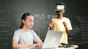 African boy wear headset to enter in metaverse while young beautiful academic student writing, coding, programming system on table with laptop or device placed. innovative education. Edification - Powered by Shutterstock - Get 15% off with code: PIKWIZARD15