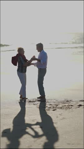 Elderly couple dancing on the beach at sunset