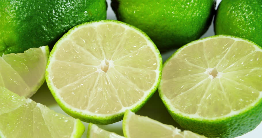 Ripe Lime Fruits with Slices and Lime Halves Slowly Rotating on a White Background. Macro Video Shooting