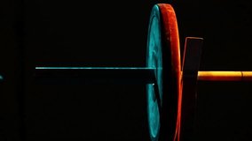 Close-up of athlete's hands securing a collar on a loaded barbell. Dark, moody gym setting with dramatic blue and orange lighting highlights the intense preparation. - Powered by Shutterstock - Get 15% off with code: PIKWIZARD15