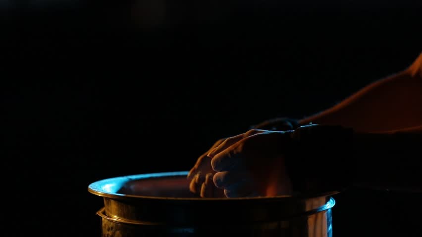 Close-up: Hands clap, creating a cloud of chalk over a metal container. Dramatic yellow and blue rim lighting highlights slow-motion particle dispersion.