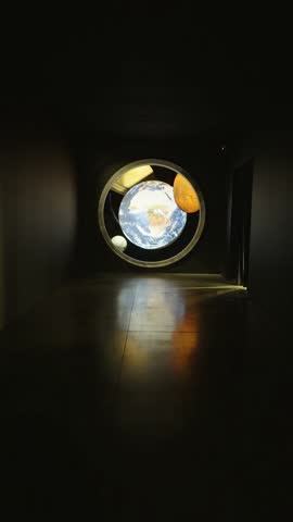 Close-up shot of a detailed miniature model depicting Earth with visible continents and oceans, its Moon, Saturn with its prominent rings, and another textured, rocky planet, all encased within a