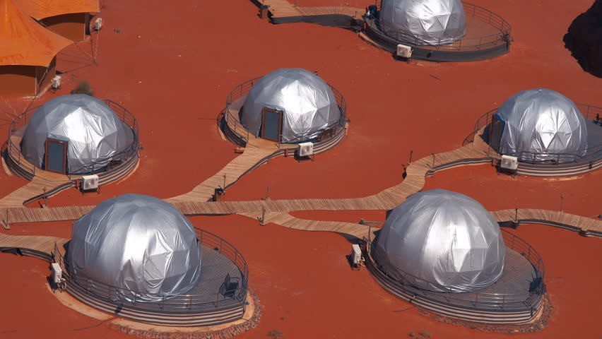 Top-down view of futuristic dome structures and tents on red ground, resembling a Mars colony base.