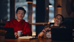 Two night managers drinking coffee at dark workplace closeup. Friendly woman man talking flirting at office coworking late evening. Smiling colleagues discussing work relaxing at workspace sipping tea - Powered by Shutterstock - Get 15% off with code: PIKWIZARD15