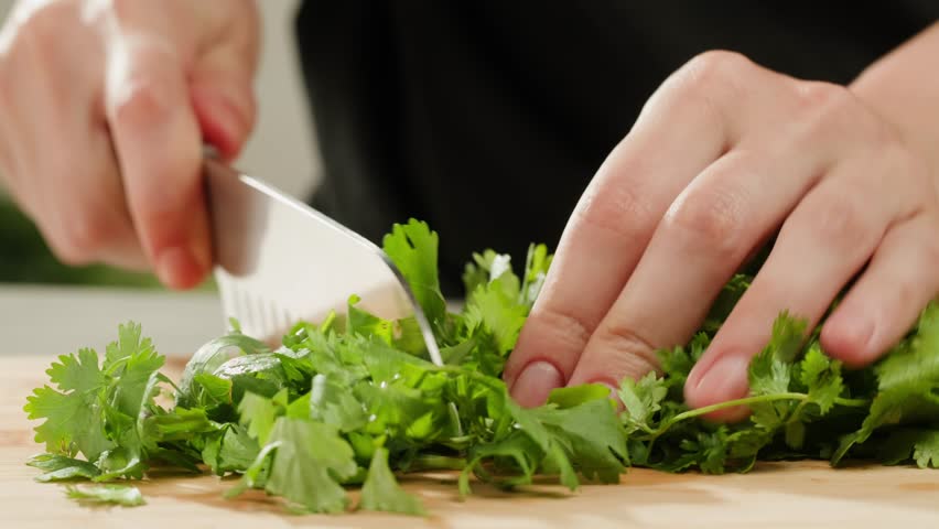 Cilantro parsley cutting by knife close up, chef chop cut coriander aromatic, traditional asian and Mexican cuisine herb studio shot.