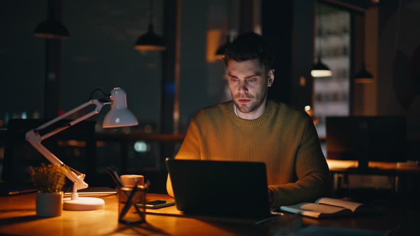 Late worker frustrated mistake online project at night workspace closeup. Tired businessman closing computer lid disappointed email at evening. Overloaded man entrepreneur feeling tensed on deadline.