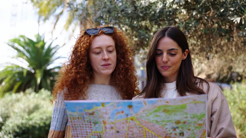 Young only women friend looking travel map in hands in front of Sagrada Familia in Barcelona. Beautiful mixed race girl at European city enjoying vacation happy and smiling. Funny tourism smile people