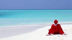 Man in Santa Claus Hat sitting with outstretched hands on the beach. Christmas vacation on islands. Winter holidays. Vertical footage - Powered by Shutterstock - Get 15% off with code: PIKWIZARD15