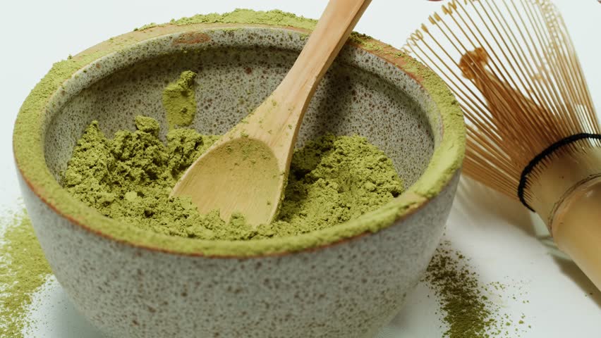 Matcha green tea cooking process, japanese powder green tea in a bowl with bamboo whisk, macro close up in cafe of powder green tea. 