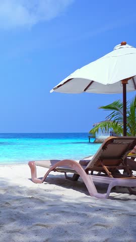 White sun umbrella and chairs at shore. Perfect summer vacation. Vertical footage