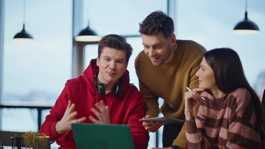Startupers discussing project online talking to laptop webcam in creative agency office closeup. Smiling business team video calling. Friendly colleagues brainstorming at virtual meeting at workplace.