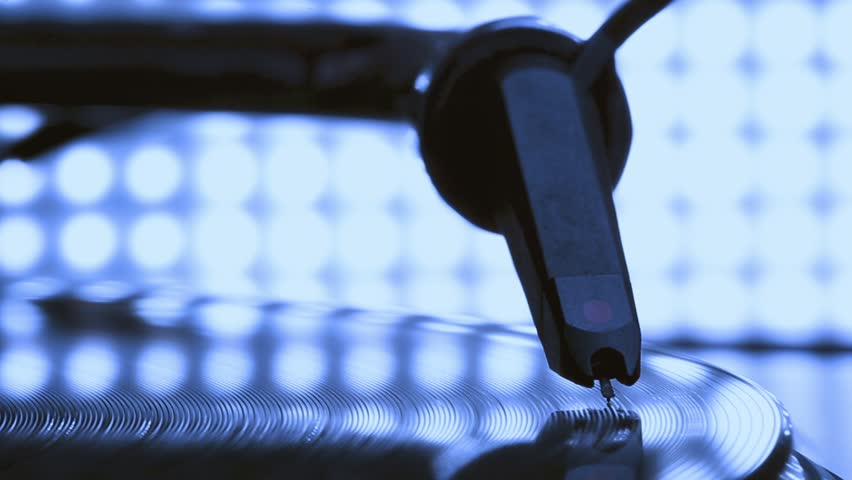 DJ headshell on spinning turntable. Listening the music on vinyl. Closeup. Blue tone