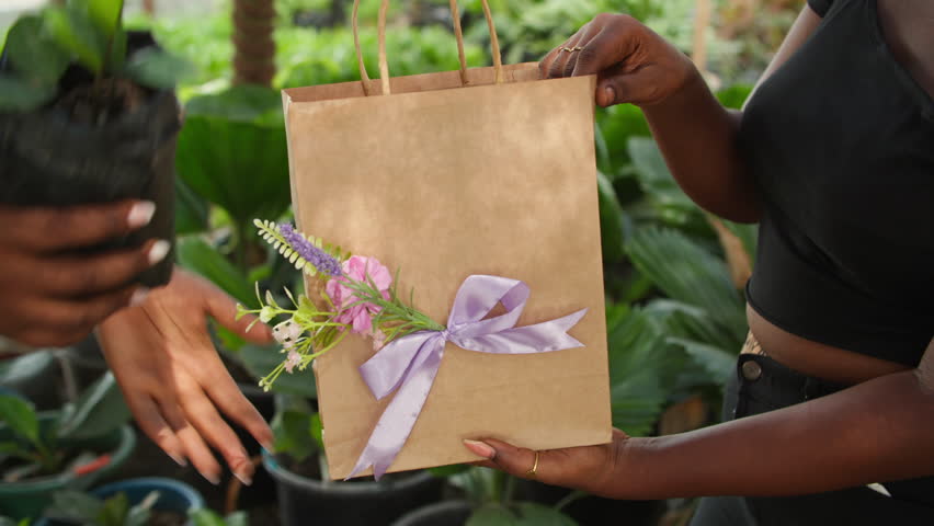Eco-friendly, sustainable green shopping, a customer buys fresh plants in a paper bag from a nursery.