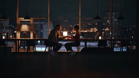 Couple dining in cozy restaurant with night city view. Happy spouses talking at romantic evening date sitting luxury cafe table together. Love pair enjoy relationship spending time in dark cafeteria. - Powered by Shutterstock - Get 15% off with code: PIKWIZARD15