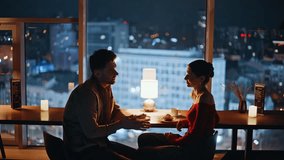 Loving people talking in restaurant with night city view closeup. Bonding happy couple enjoying romantic evening date at cozy cafeteria. Smiling man taking hand beloved woman feeling love tenderness. - Powered by Shutterstock - Get 15% off with code: PIKWIZARD15