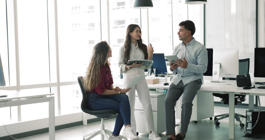 Young diverse small business team brainstorming on project creative solutions, discussing work plan, tasks for day, talking in modern office workspace, gathering in circle at workplace