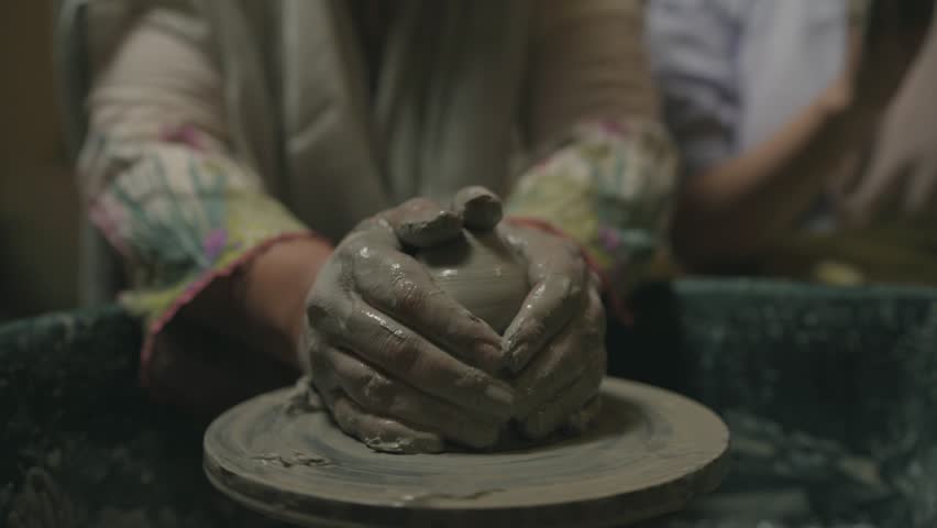 sculpting spinning clay with firm hands in pottery process