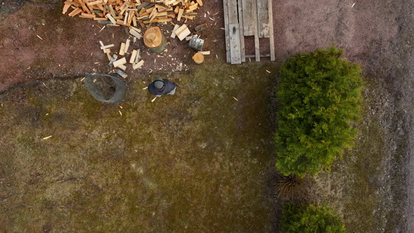 Aerial hyperlapse of a person chopping firewood at a renewable home, spring day