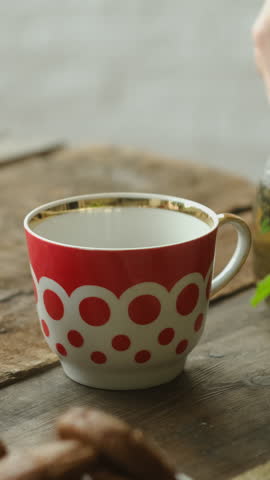 Vertical video. Afternoon tea time. Pouring brewed herbal green tea with fresh mint from teapot. 