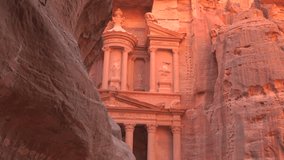 The ancient Treasury, Al-Khazneh, carved into sandstone rock walls and viewed through the Siq gorge, bathed in warm sunset light in Petra, Jordan. - Powered by Shutterstock - Get 15% off with code: PIKWIZARD15