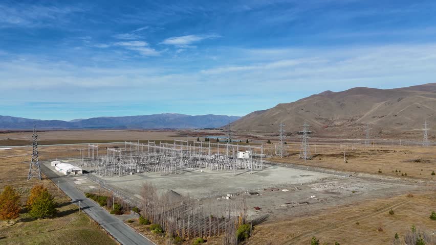 Aerial footage of a power substation at Lake Tekapo, New Zealand, showcasing high-voltage infrastructure against a mountainous autumn landscape